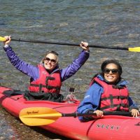 two people in a tandem kayak smiling at the camera