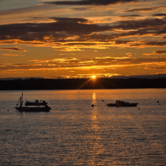 a sunset behind a boat on a body of water
